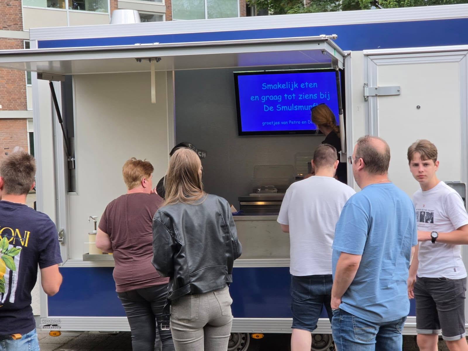 Gasten genieten van een puntzak verse friet bij De Smulsmurf